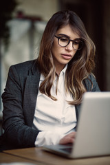 Young modern woman sitting in cafe and using laptop.