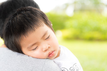 Closeup portrait of cute little girl sleeping on mothers shoulder in garden background, happy young loving family, new life concept.