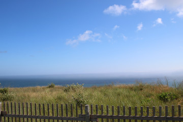 Ocean landscape with fence and field in the foreground