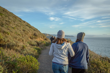 Two women walking a coastline trail