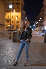 Pretty girl posing at night in Rome, Italy. Attractive model on the background of narrow ancient Roman streets