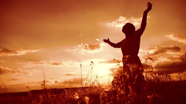 woman praying on her knees. Girl folded her hands in prayer silhouette at sunset. slow motion video. lifestyle Girl folded her hands in prayer pray to God. the girl praying asks forgiveness for sins
