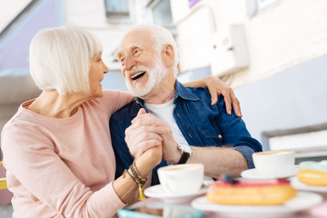 Life together. Low angle of cheerful senior couple holding hands and laughing