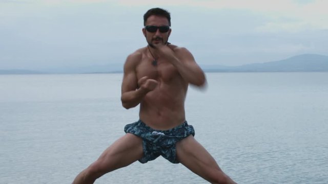Muscular Man Practicing Martial Arts at the Sea Coast