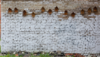 A row of birdhouse on brick wall.