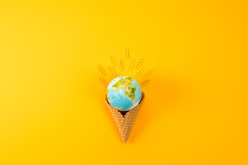 top view of earth globe in waffle cone with paper clips on yellow