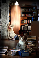 Beautiful girl reading a book in the library, next to the cat