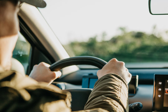 Close-up. The driver's hand on the steering wheel. The driver or traveler or tourist is driving a car. Everyday riding or traveling.