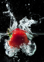 Sweet red pepper splashing in the clear water
