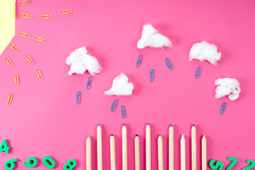 Top view of rainy landscape composition arranged of paper clips, pencils and cotton on pink
