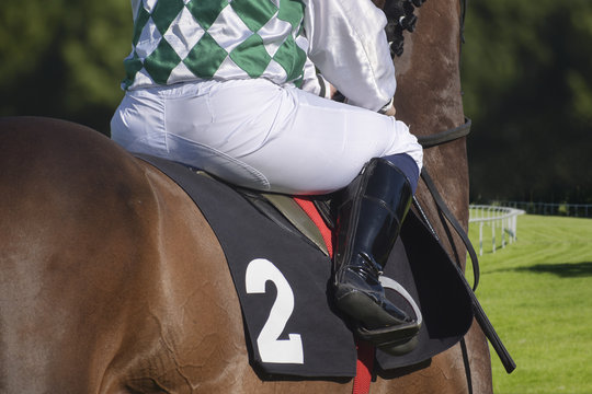 jockey on a brown horse from behind at a gallop race on a grass track
