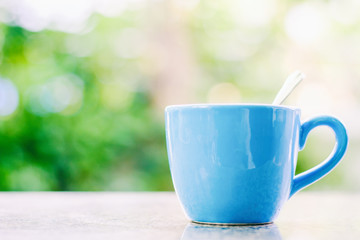 Blue cup of coffee against blurred natural background for drinking and beverages concept