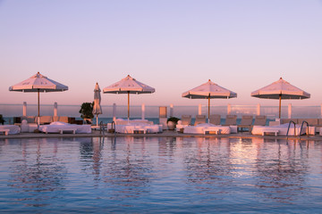 Pastel Sunset Light over Swimming Pool and Sun Beds.