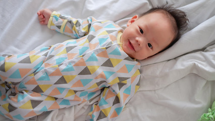 Asian boy is lying in the bed.