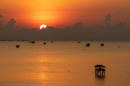 Fototapeta scenic of sunrise sky with seascape silhouette fisherman hut