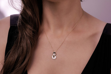 Girl wearing a gold necklace with a snowman pendant