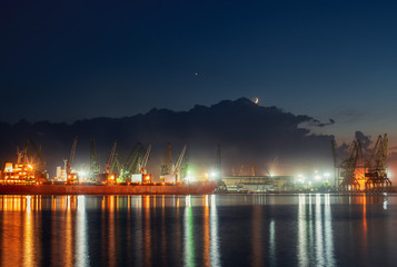 Fototapeta na wymiar Industrial cranes and cargo ships in Varna port, Bulgaria at sunset