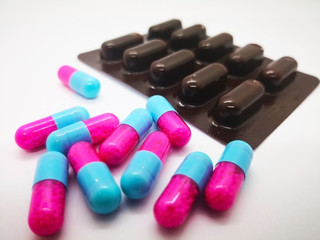 Medication and healthcare concept. Many pink-blue capsules of Itraconazole 100 mg., used to treat infections caused by fungus, White background, selective focus and copy space.