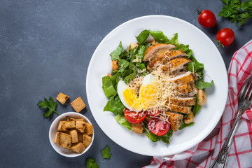 Caesar salad with chicken breast and tomatoes.