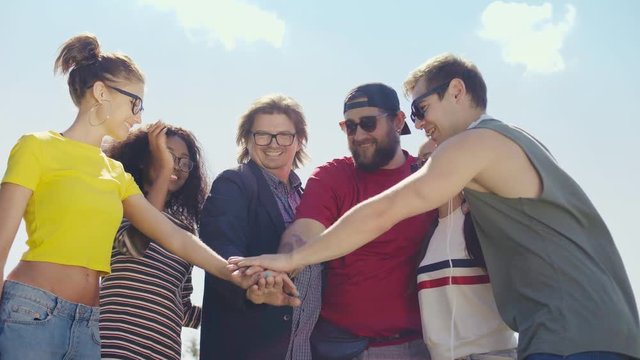 Happy friends putting their hands together and smiling