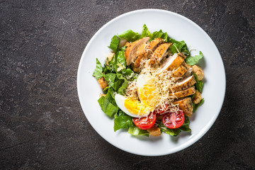 Caesar salad with chicken breast and tomatoes.