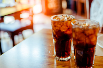 Two glass soft drink with ice in restaurant background.