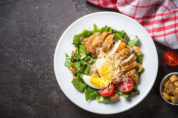 Caesar salad with chicken breast and tomatoes.