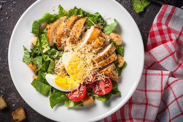 Caesar salad with chicken breast and tomatoes.