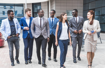 Successful company with happy workers. Men and women in business suits stand with their arms crossed against the background of skyscrapers