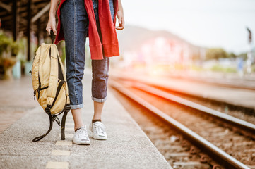 Close Up of A woman's legs are waiting for the train at the train station with her backpack.