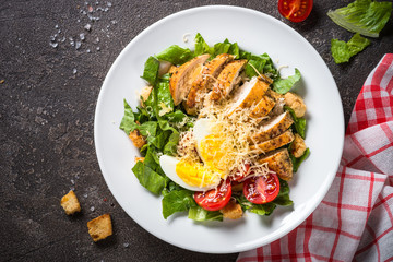 Caesar salad with chicken breast and tomatoes.
