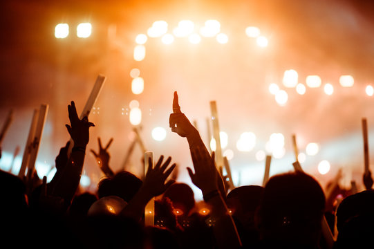 silhouettes of hand in concert.Light from the stage.