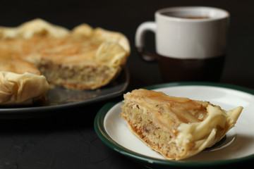 Apple cake with almond cream on a dark background. Baked cake with coffee and teaspoon.  Pie for the whole family on a sunny day