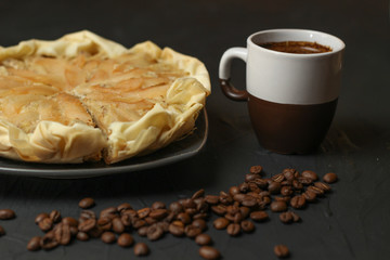 Apple cake with almond cream on a dark background. Baked cake with coffee nd coffee beans. Pie for the whole family on a sunny day
