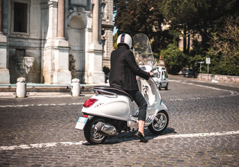 Modern and fashionable woman on a scooter / vespa in Roma Italy on a beautiful day with historic background (fontana del Gianicolo)