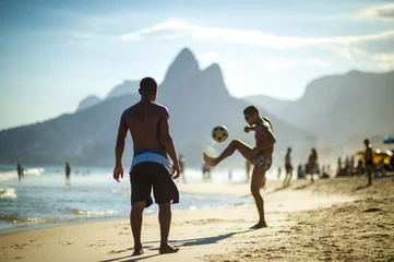 Poster Unrecognizable young Brazilians play a game of beach football keepy-uppy "altinho" on the shore of Ipanema Beach. © lazyllama