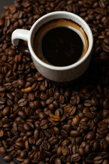 A cup of coffee with coffee beans on a dark background. A delicious fragrant coffee of the best varieties