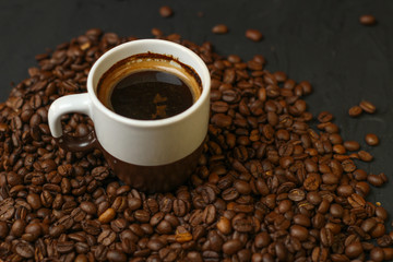 A cup of coffee with coffee beans on a dark background. A delicious fragrant coffee of the best varieties