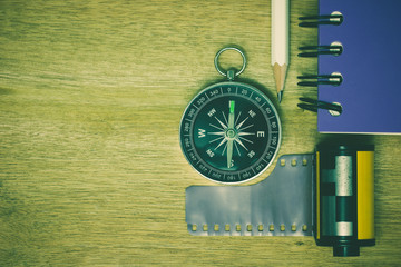 Compass photographic film and notebook with pencil placed on brown wooden table. The concept of...