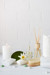Spa setting and health care items, body oil, soap, candles, towel with lilac flower