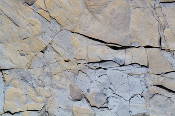 Grey stone surface texture with cracks and damages.