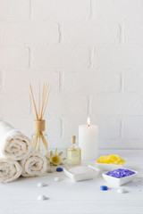Composition of spa wellness products on white background. with towel,white lily, sea salt, bath oil, sugar body scrub and candle