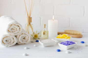 Fototapeta na wymiar Composition of spa wellness products on white background. with towel,white lily, sea salt, bath oil, sugar body scrub and candle