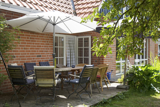 summer terrace at the house with table and many chairs under a sunshade for a meal with the whole family