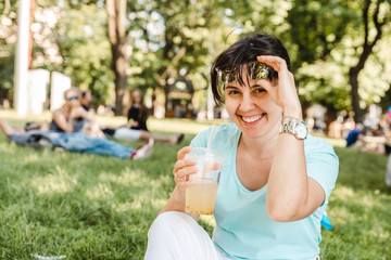 woman holding cool drink in city park. blurred background