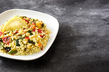 Couscous with vegetables on black stone. Copyspace