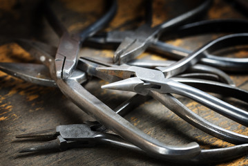 heap of pliers from a goldsmith,  tools on the jewelry workplace with copy space in the blurred...