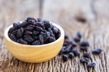 Close up raisins in bowl on wooden table background