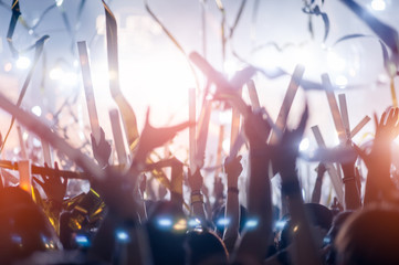 silhouettes of hand in concert.Light from the stage.confetti.the crowd of people silhouettes with...