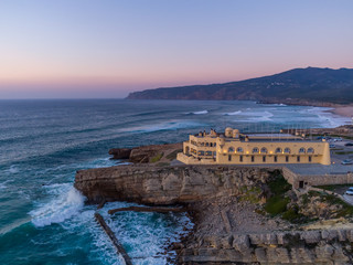 Aerial dronephoto of Praia do Guincho Beach and Hotel Fortaleza at sunset in Sintra, Portugal